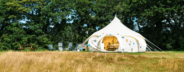 Image of a Lotus Belle bell tent pitched in a field. A luxury, canvas tent with lots of standing room & made from bespoke canvas. Perfect for camping & glamping.